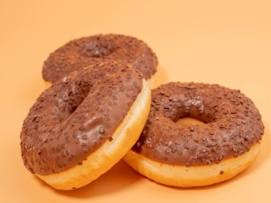 Chocolate donut with chocolate chips on an orange background. close-up.