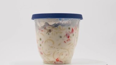 Vegetarian pasta salad in a plastic jar on a white background. Pasta salad close up.