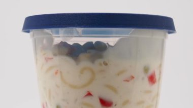 Beyaz arka planda plastik bir kavanozda vejetaryen makarna salatası. Makarna salatası..