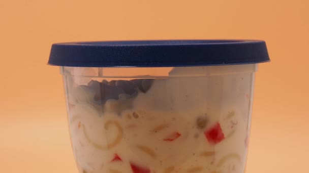 素食意大利面沙拉在一个塑料罐子的橙色背景 意大利面沙拉关门了 — 图库视频影像