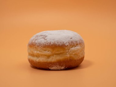 Freshly baked and dusted with powdered sugar German donuts. Donut berliner or krapfen on orange background.