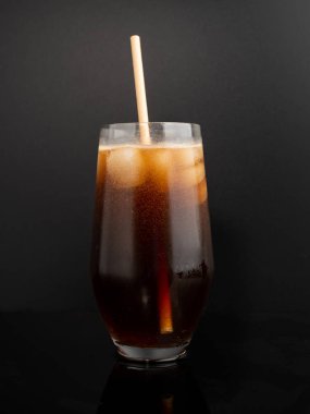 Glass of cola with ice on a black background. Close-up.