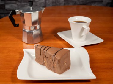 A piece of chocolate cake and a cup of coffee on a wooden table. Dessert.