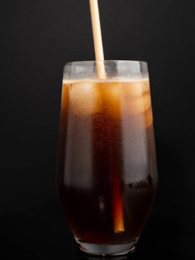 Glass of cola with ice on a black background. Close-up.
