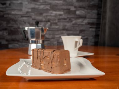 A piece of chocolate cake and a cup of coffee on a wooden table. Dessert.