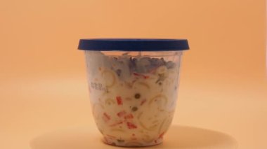 Turuncu arka planda plastik bir kavanozda vejetaryen makarna salatası. Makarna salatası..