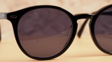 Stylish sunglasses. Dark-framed sunglasses rotate on a sandy background. Close-up.
