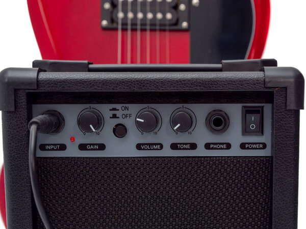 Red electric guitar and classic amplifier. Musical instrument guitar. Close-up.