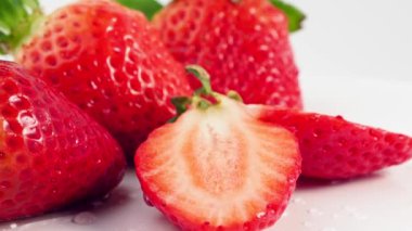 Beyaz arka planda olgun sulu çilekler dönüyor. Yakın plan..