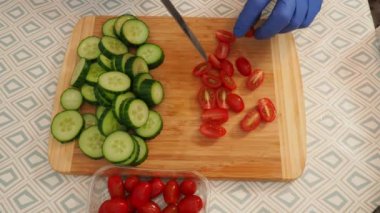 Salatalık ve domatesler salata için bir kesim tahtasının üzerinde kesilir. yakın plan.