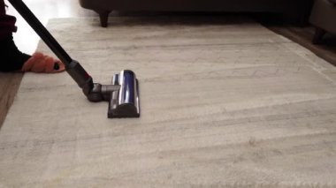 Bir kadın modern bir elektrikli süpürgeyle halı süpürüyor. Ev temizliği.