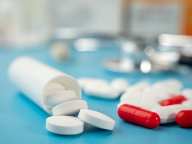 Mavi arka planda ilaçlar. Kapsüller, tabletler ve ampuller. Yakın plan..