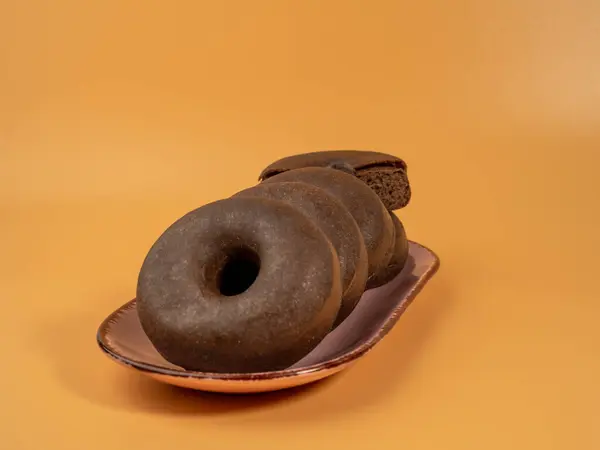Frischer Dunkler Vegetarischer Donut Auf Einem Teller Auf Orangefarbenem Hintergrund — Stockfoto