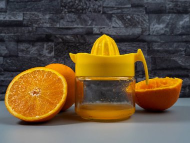 Olgun portakal suyu ile portakal sıkacağı. Taze meyve suyu. Gri arkaplan.