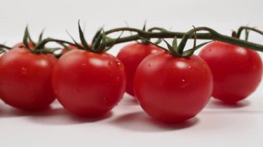 Beyaz arka planda izole edilmiş yeşil saplı bir avuç taze kırmızı domates. Domatesler yakın plan..