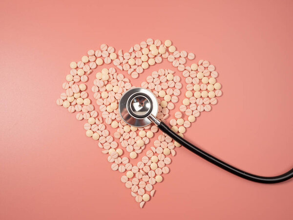 Pink pills and a stethoscope on a pink background. Medical tablets. Pills close-up.