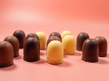 Pembe arka planda çikolata kaplı marşmelov. Yakın plan.