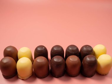 Pembe arka planda çikolata kaplı marşmelov. Yakın plan.