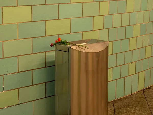 A bouquet of flowers in a trash can. Trash can in the underpass.