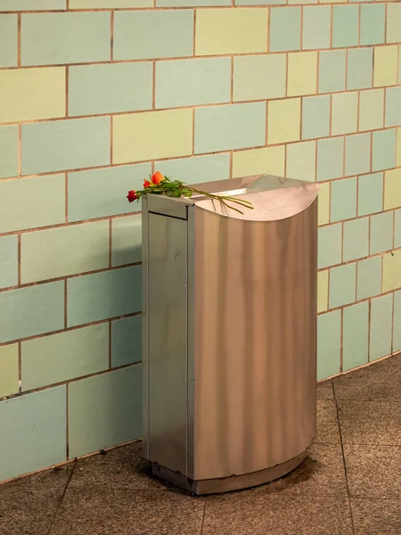 A bouquet of flowers in a trash can. Trash can in the underpass.