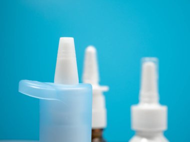 Burun spreyi şişeleri mavi arka planda, soğuk algınlığını burun spreyiyle tedavi ediyor. Tıbbı yakın çekim.