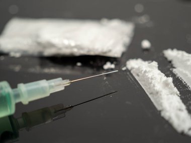 Siyah arka planda iğne ve kokain tozu için şırınga. Uyuşturucu ve para..