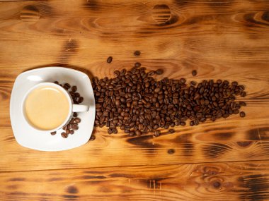 Bir fincan kahve ve ahşap arka planda kızarmış kahve çekirdeği. Bir fincan kahve yakın çekim..