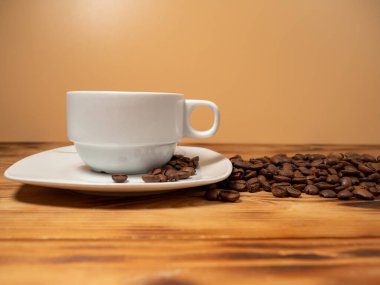 Bir fincan kahve ve ahşap arka planda kızarmış kahve çekirdeği. Bir fincan kahve yakın çekim..