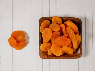 Ahşap arka planda tahta bir kase kurutulmuş kayısı, seçici bir odak. Kurutulmuş kayısılar yakın..