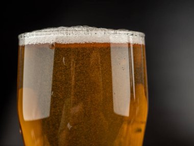 Karanlık bir arka planda bir bardak soğuk bira. Bir bardak yakın plan bira..