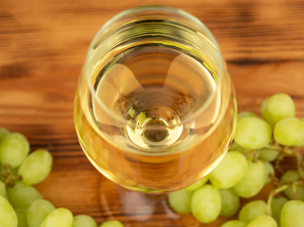 stock image Glass of white wine and grapes on a wooden background. Close-up glass of white wine.