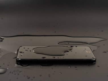 Smartphone 'un üzerine su döküldü. Akıllı telefon suya düşmüştü. Siyah arkaplanda ıslak akıllı telefon.