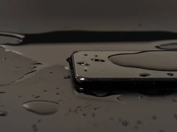 stock image Water has been spilled on the Smartphone. The smartphone fell into the water. Wet smartphone on a black background.