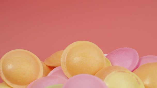 さまざまな色のUfoの形の甘いキャンディーはピンクの背景で回転します シャーベットと宇宙船の形をしたシュガーペーパーフライングソーサー — ストック動画