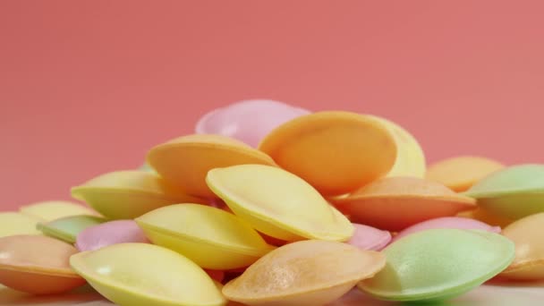 不同颜色的Ufo形状的甜糖果在粉色背景上旋转 糖纸飞碟 形状如一艘装有雪茄酒的宇宙飞船 — 图库视频影像