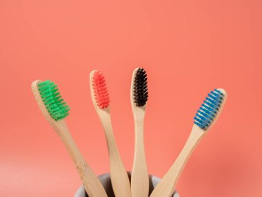 Bambu diş fırçaları farklı renklerde. Pembe arka planda tahta diş fırçası. Diş fırçasını yakın çekim.