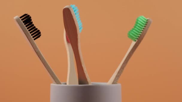 Бамбукові Зубні Щітки Різних Кольорів Обертаються Помаранчевому Фоні Дерев Яна — стокове відео