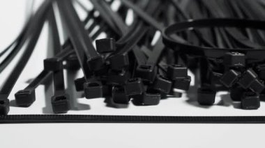 Beyaz arka planda plastik siyah kravatlar. Kablolar için plastik bağlar.