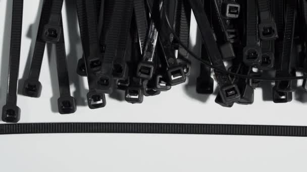 白い背景にプラスチック製の黒いネクタイ ケーブル用プラスチックタイ — ストック動画