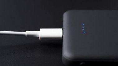 Mobil cihazları siyah arkaplanda şarj etmek için güç bankası. Güç kaynağı olan akıllı telefon şarjı. Mobil aygıtlar için dış pil.