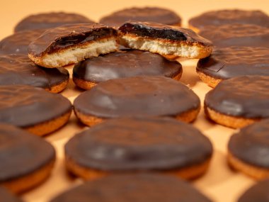 Koyu çikolata ve portakal reçelli kurabiyeler. Turuncu arka planda siyah çikolatalı kurabiyeler..