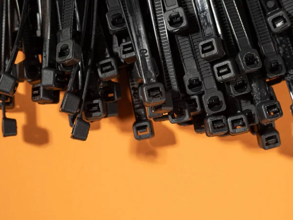 Schwarze Krawatten Aus Plastik Auf Orangefarbenem Hintergrund Kunststoffbänder Für Kabel — Stockfoto