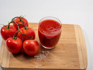 Beyaz arka planda bir bardak domates suyu. Yeni hazırlanmış domates suyu..