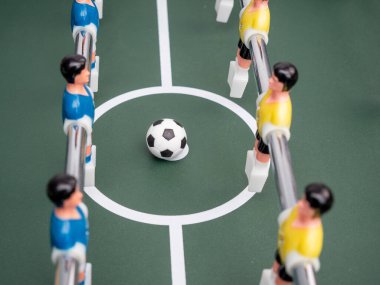 Birkaç oyuncunun yakın çekimi ve langırt masasında bir futbol topu. Masa futbolu.