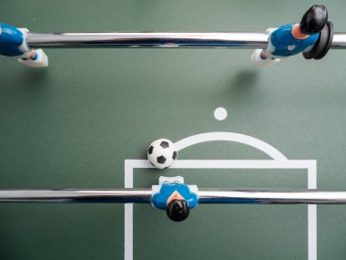 Birkaç oyuncunun yakın çekimi ve langırt masasında bir futbol topu. Masa futbolu.