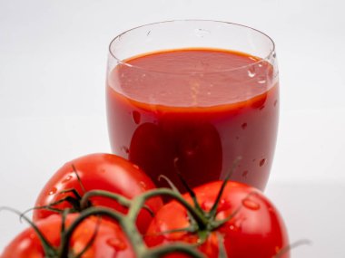 Beyaz arka planda bir bardak domates suyu. Yeni hazırlanmış domates suyu..