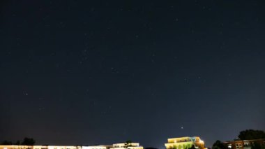 Gece yıldızlı gökyüzü şehrin üzerinde. Evlerin çatısının üstündeki yıldızlı gökyüzü.