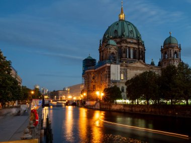 Alacakaranlıkta Berlin Nehri 'nin manzarası. Gece fenerlerinden nehir boyunca ışık izleri var..