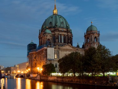 Alacakaranlıkta Berlin Nehri 'nin manzarası. Gece fenerlerinden nehir boyunca ışık izleri var..