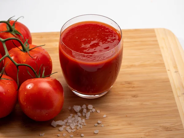 一杯番茄汁和西红柿放在白色背景上 新鲜准备的番茄汁 图库图片